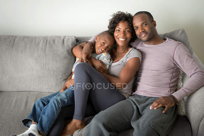 Retrato de padres e hijo sentado en el sofá - foto de stock