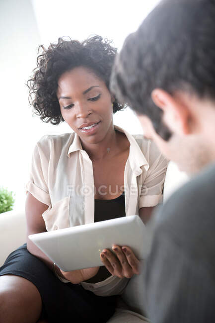 Office workers on sofa looking at digital tablets — Stock Photo