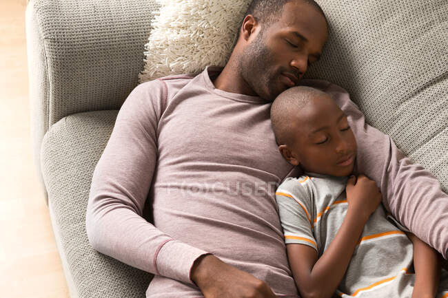 Padre e hijo durmiendo en el sofá - foto de stock
