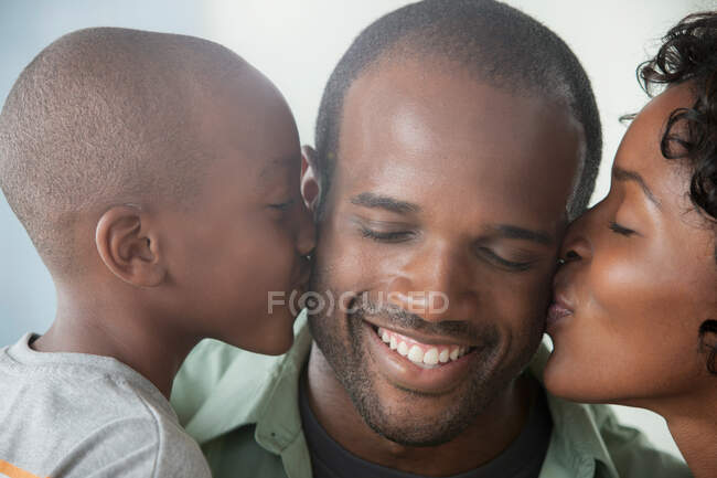 Мальчик и женщина целуют мужчину в щеки — стоковое фото