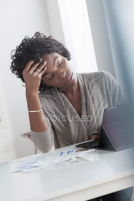 Mujer adulta pagando facturas usando tableta digital, cabeza en manos - foto de stock