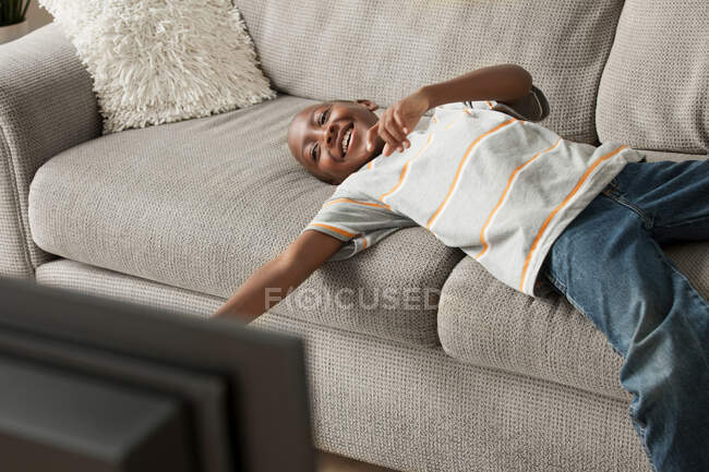 Хлопчик лежить на дивані дивитися телевізор — стокове фото