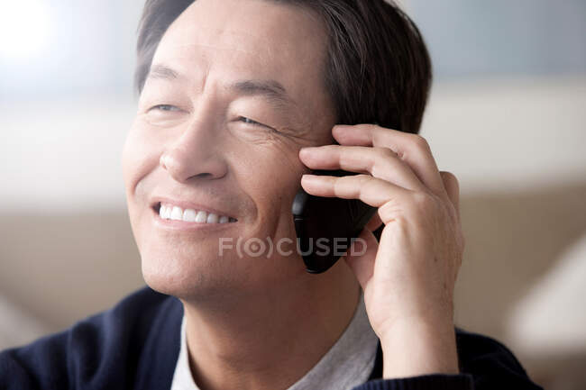 Зрілий азіат користується мобільним телефоном. — стокове фото