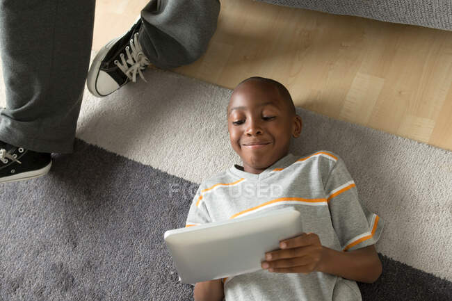 Мальчик лежит на полу с помощью цифрового планшета — стоковое фото