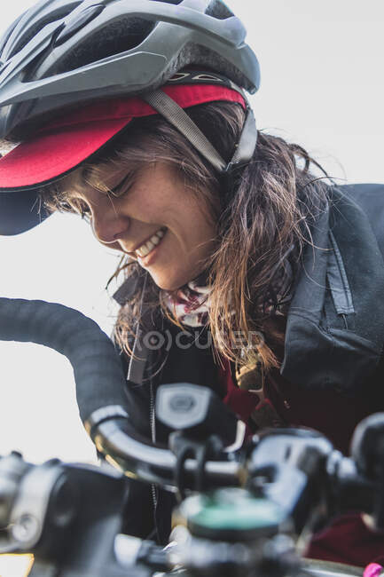Жінка на велосипеді, одягнена в шолом, посміхається — стокове фото
