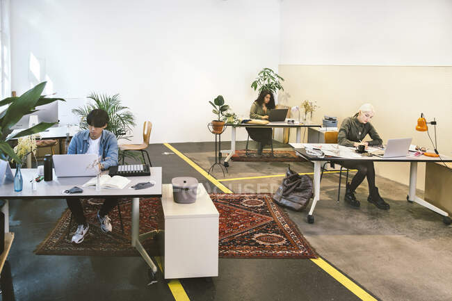 Menschen, die im Co-Working Space arbeiten, mit sozialer Distanzierung in pla — Stockfoto