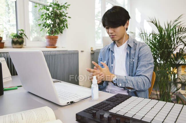 Чоловік використовує дезінфікуючий засіб для рук за своїм столом — стокове фото