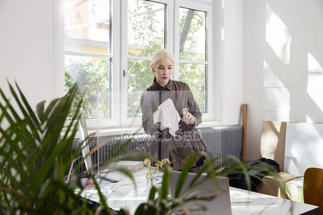 Woman cleaning protective screen partition around desk — Stock Photo