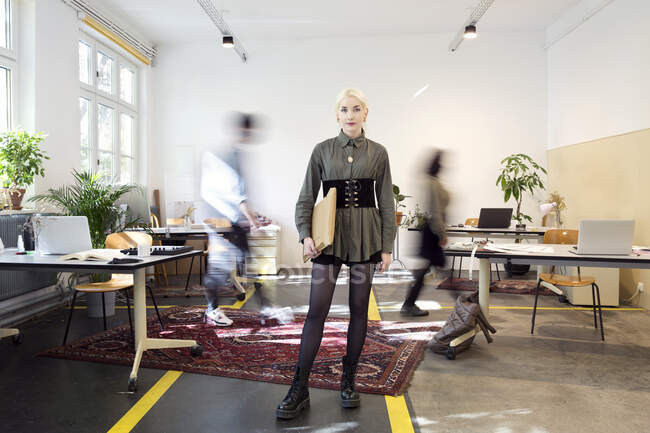 Молода жінка стоїть в зайнятому творчому кооперативному просторі — стокове фото