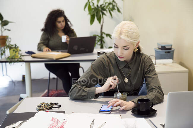 Junge Frau beim Mittagessen am Schreibtisch — Stockfoto