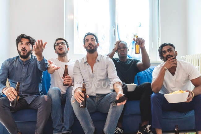Hommes regardant le sport à la télévision ensemble, l'air déçu — Photo de stock