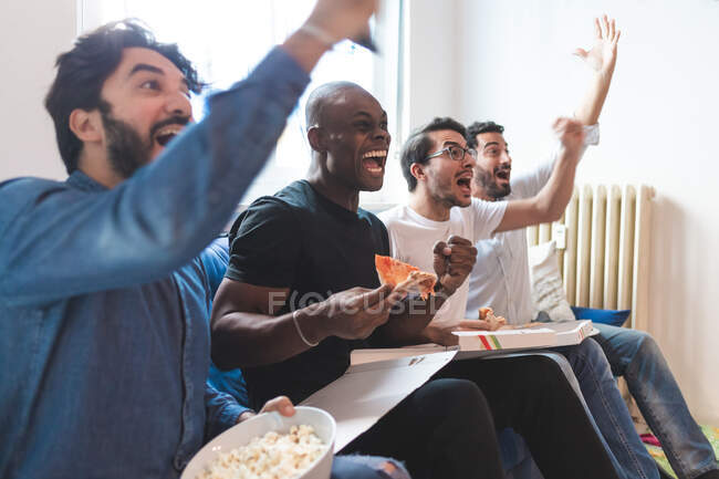 Men eating pizza and cheering — Stock Photo