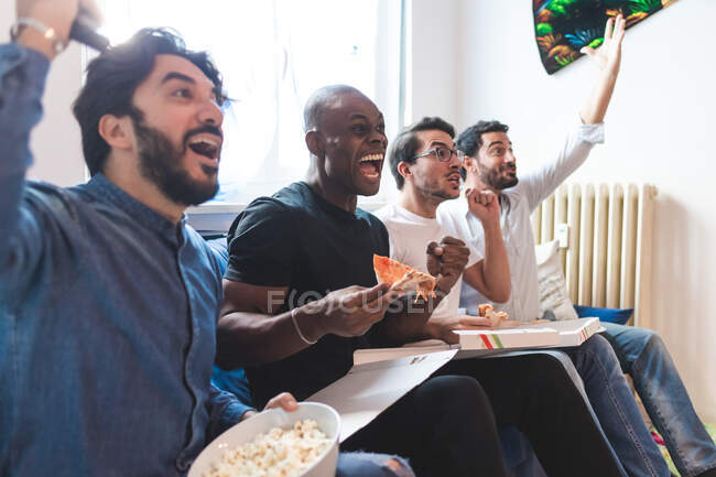 Homens comendo pizza e aplaudindo — Fotografia de Stock
