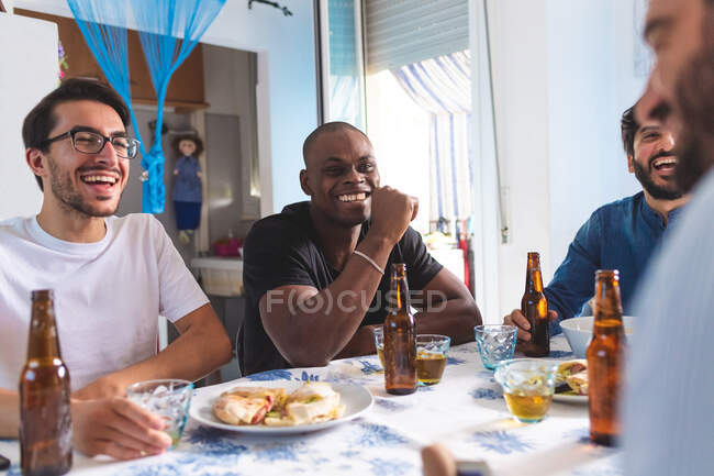 Amigos varones socializando con comida y cerveza - foto de stock