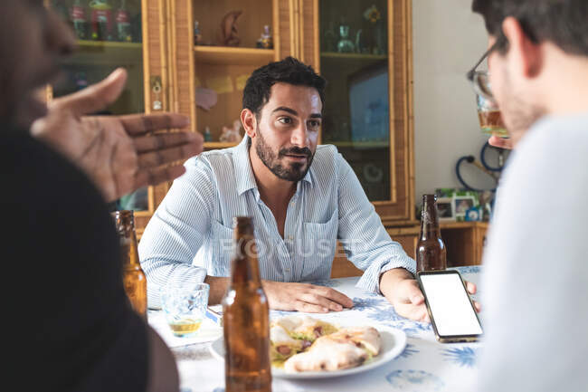 Male friends having discussion over food — Stock Photo