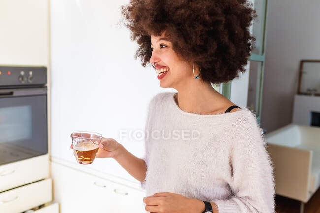 Giovane donna che beve qualcosa a casa — Foto stock
