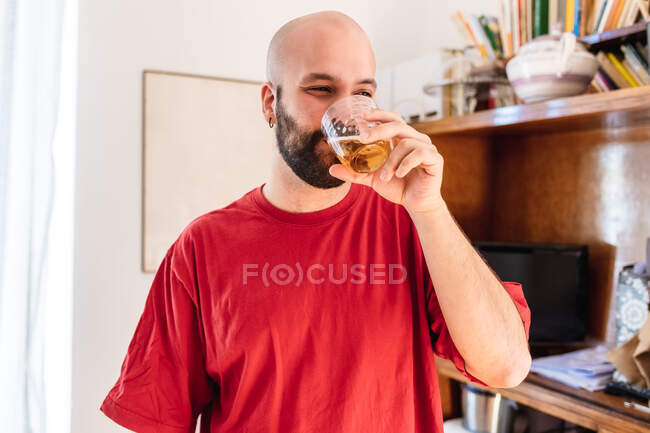 Jovem tomando uma bebida em casa — Fotografia de Stock