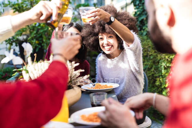 Freunde essen gemeinsam im Freien, stoßen mit drin an — Stockfoto