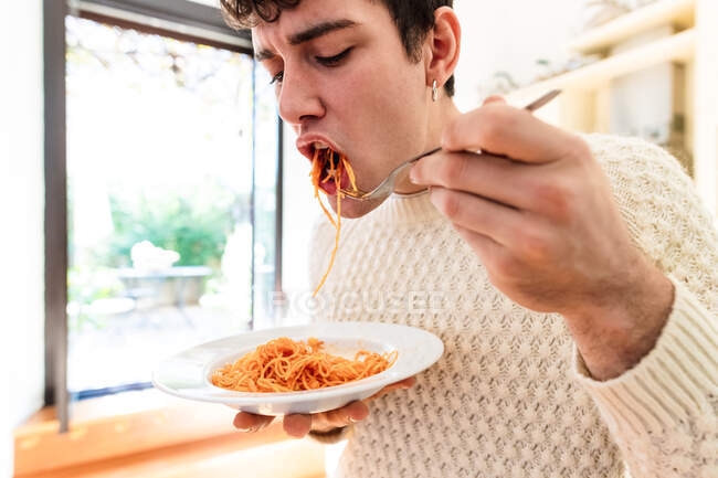 Joven comiendo espaguetis - foto de stock