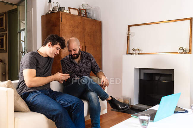 Amigos varones en casa, mirando el teléfono - foto de stock