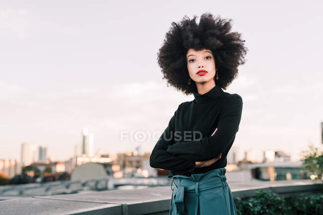 Retrato de una mujer de negocios con los brazos cruzados, ciudad en segundo plano - foto de stock