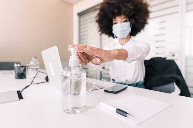 Geschäftsfrau benutzt Händedesinfektionsmittel an ihrem Schreibtisch — Stockfoto