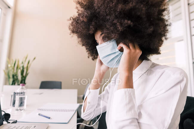 Businesswoman putting on face mask — Stock Photo