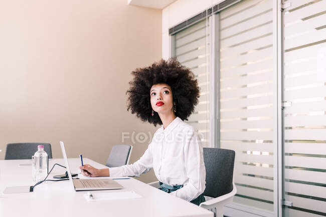 Femme d'affaires seule au bureau, levant les yeux — Photo de stock
