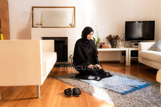 Mujer musulmana joven arrodillada durante la oración - foto de stock