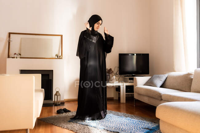 Молода мусульманка, що стоїть з піднятими руками під час молитви — стокове фото