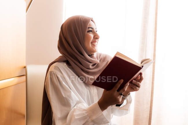 Joven musulmana, leyendo y sonriendo - foto de stock
