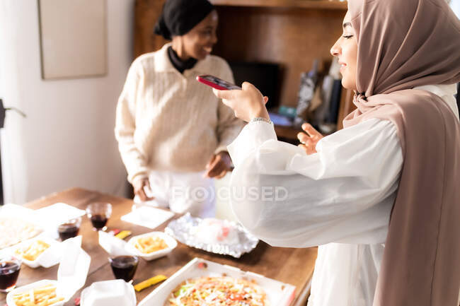 Jeune femme prenant des photos de repas à emporter avec des amis — Photo de stock