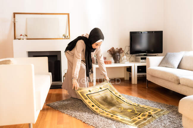 Young muslim woman preparing mat for prayer — Stock Photo