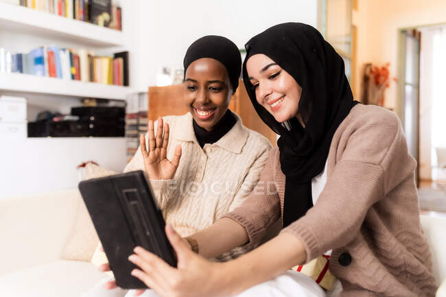 Dos mujeres jóvenes usando tableta digital para videollamada - foto de stock
