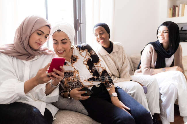 Quatro jovens muçulmanas, a olhar para o telemóvel — Fotografia de Stock