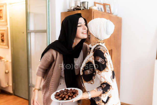 Mujer saludo amigo con plato de dátiles - foto de stock