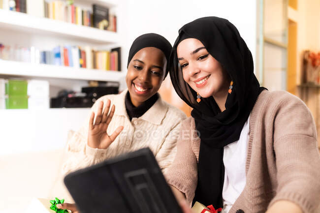 Dos mujeres musulmanas jóvenes usando tableta para una llamada - foto de stock