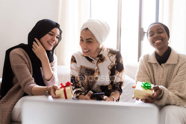 Three young muslim women on video call with gifts — Stock Photo