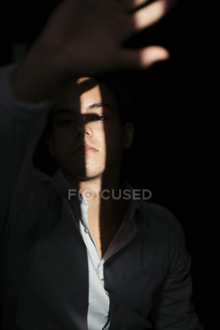 Menino adolescente em interior escuro com luz solar — Fotografia de Stock