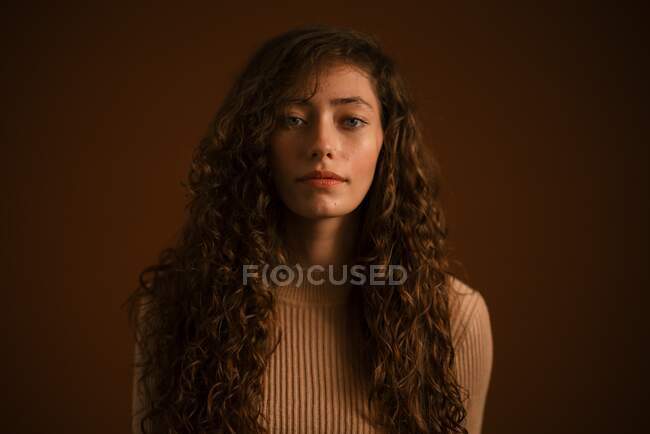Portrait studio de jeune femme aux longs cheveux bouclés — Photo de stock