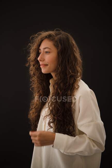 Студийный снимок улыбающейся молодой женщины с длинными вьющимися волосами — стоковое фото