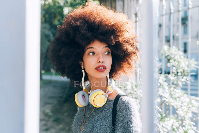 Молода жінка на відкритому повітрі, дивиться вбік, носить навушники — стокове фото