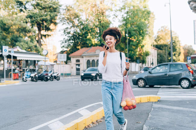 Jeune femme au téléphone, marchant dans la rue — Photo de stock