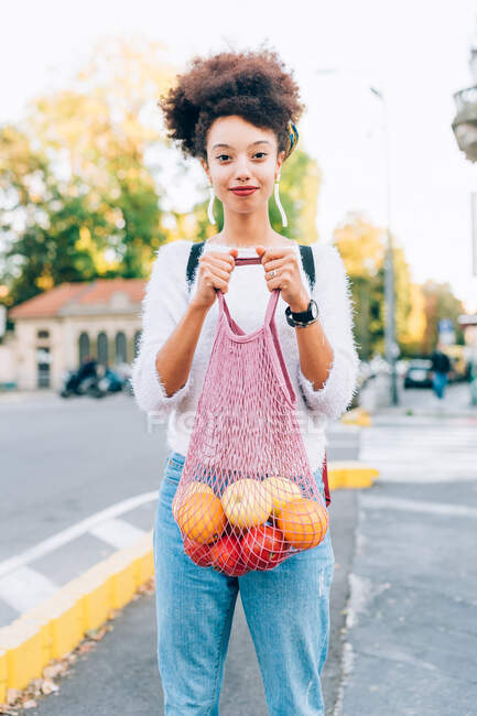 Young woman holding fruit in string bag — Stock Photo
