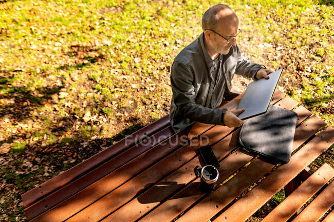 Uomo che si prepara a lavorare sul tavolo da picnic nel parco — Foto stock