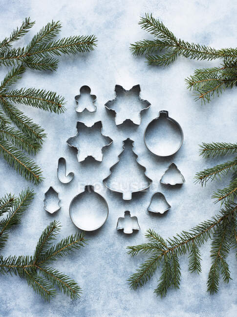 Still life of metal cookie cutters with Christmas tree twigs — Stock Photo
