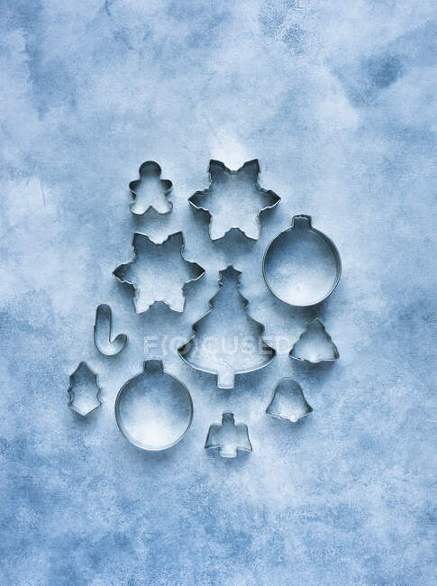 Cortadores de biscoitos de metal de diferentes formas no fundo azul — Fotografia de Stock