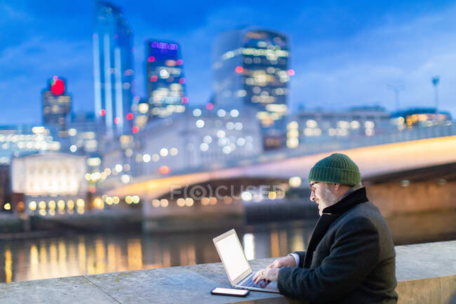 Man working on laptop by River Thames, London, UK — Stock Photo