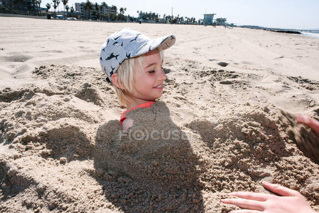 Мальчика хоронят в песке на пляже — стоковое фото