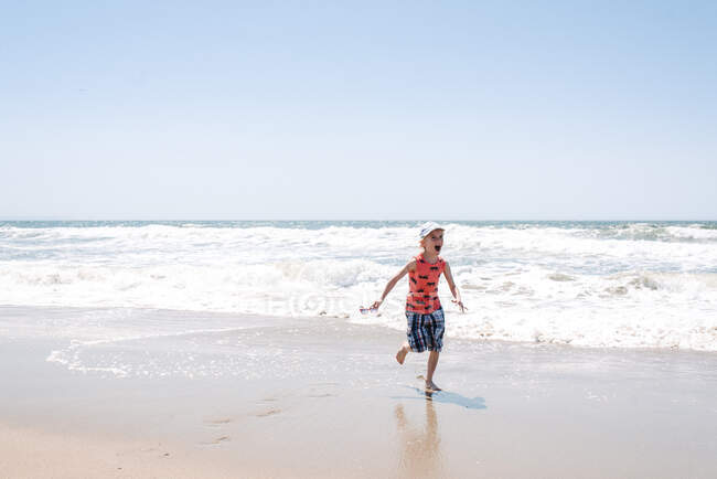 Ragazzo in riva al mare, in fuga dalle onde — Foto stock